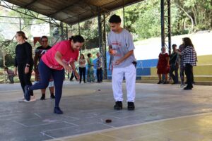 Participante do Programa Terceira Idade joga amarelinha ao lado de jovem do projeto Comunidade em Movimento, na quadra da Fundação Julita