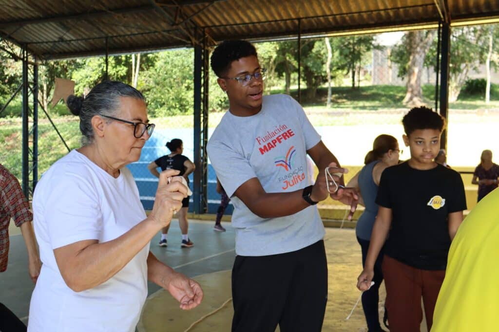 Jovem do Comunidade em Movimento ensina brincadeira com barbante a participante do Programa Terceira Idade na quadra da Fundação Julita