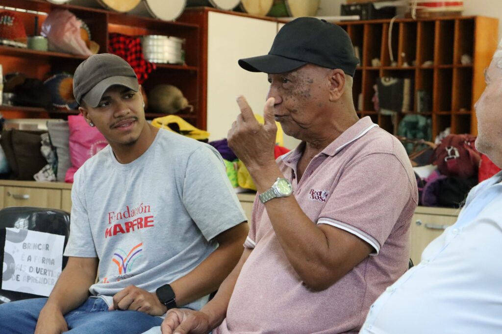Jovem do Comunidade em Movimento escuta participante do Programa Terceira Idade contar memórias de infância em roda de conversa